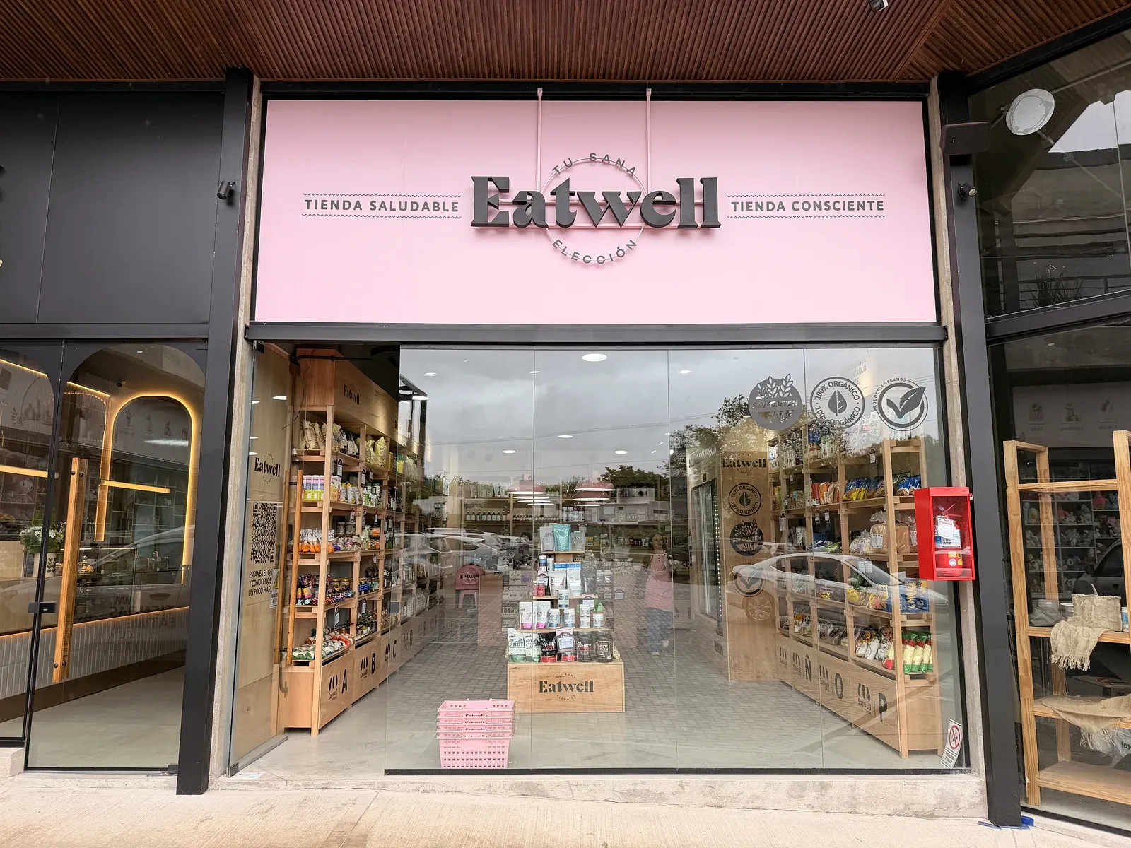 Fachada de la Tienda Eatwell de La Calera, con el cartel rosa de la marca y la vidriera con góndolas