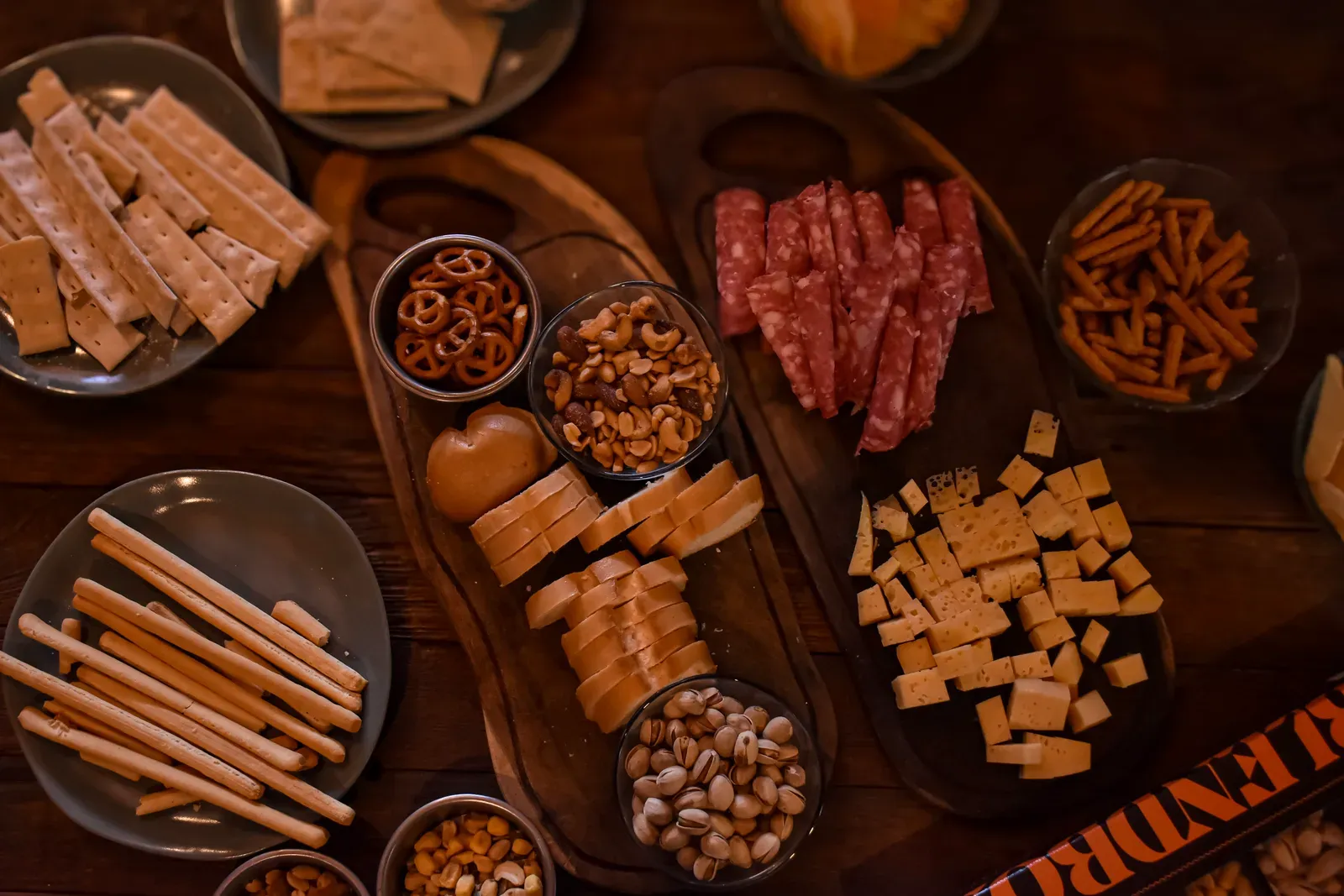 Vista cenital de una picada con fiambres, quesos, frutos secos y panes para compartir